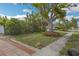 Lush front yard with tropical landscaping, mature trees, and walkway at 5101 Town N Country Blvd, Tampa, FL 33615