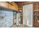 Utility room featuring a water heater, open wood framing, and built-in wood shelving at 5101 Town N Country Blvd, Tampa, FL 33615
