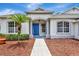 Close-up of a home's entry with a blue front door, a palm tree, and clean landscaping at 11018 Pine Lilly Pl, Lakewood Ranch, FL 34202