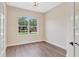 Office space with hardwood flooring, natural light from a large window, and glass French doors at 11018 Pine Lilly Pl, Lakewood Ranch, FL 34202