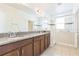 Bathroom featuring double vanity with granite counters, wood cabinets, and a glass-enclosed shower at 32717 Coldwater Creek Loop, Wesley Chapel, FL 33545