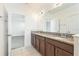 Bathroom vanity with granite counters, dark wood cabinets, tile floor, and large mirror at 32717 Coldwater Creek Loop, Wesley Chapel, FL 33545