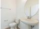 Powder room with a pedestal sink, modern faucet, oval mirror, and tiled floor at 32717 Coldwater Creek Loop, Wesley Chapel, FL 33545