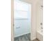 All-white bathroom showing a bath and shower with a small window and blind at 5254 Suncatcher Dr, Wesley Chapel, FL 33545