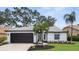 Charming home featuring a lush lawn, updated garage door, and a well-manicured tropical landscape at 9555 Knightsbridge Cir, Sarasota, FL 34238