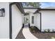 Inviting entryway with a modern white door, fresh landscaping, and sleek black gutters and light fixtures at 9555 Knightsbridge Cir, Sarasota, FL 34238