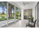 Covered patio with comfortable seating and serene views of the lush backyard and waterfront at 9555 Knightsbridge Cir, Sarasota, FL 34238