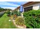 Landscaped backyard with various plants, a blue patio umbrella, grill, and green lawn at 1122 Montrose Pl # 1713, Dunedin, FL 34698