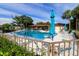 Community pool with blue umbrellas, lounge chairs, and lush landscaping on a bright, sunny day at 1122 Montrose Pl # 1713, Dunedin, FL 34698