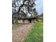 A quaint single-story home featuring a gravel driveway and mature trees in a natural setting at 5026 Osprey Ln, New Port Richey, FL 34652