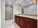 Elegant bathroom with dark wood cabinets, granite countertop, and stone accent wall in shower at 19700 Gulf Blvd # 204, Indian Shores, FL 33785