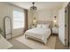 Cozy bedroom with a neutral color scheme, featuring a comfortable bed, sconces, and natural light from the window at 2913 Suncoast Plains Dr, Odessa, FL 33556