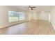 Bright living room featuring light wood floors, ceiling fan, and large window that bring in ample natural light at 221 Vermont E Ave, Bradenton, FL 34208
