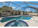 Screened-in pool area with inground pool, spa, patio seating, and lush landscaping at 2521 Carlisle Pl, Sarasota, FL 34231