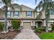 Inviting townhome with a well manicured front yard, brick driveway, and lush tropical landscaping at 26835 Juniper Bay Dr, Wesley Chapel, FL 33544