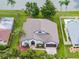 Aerial view of a light blue house with a large roof, landscaped yard, and lake access at 9246 Dayflower Dr, Tampa, FL 33647