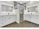 Bathroom featuring dual vanity sinks, large lighted mirrors, and a glass shower enclosure at 9573 Migue Cir, Port Charlotte, FL 33981