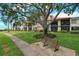 A lovely green lawn, large shade tree, and seating bench in front of a condo building with balconies at 6218 Palma Del Mar S Blvd # 103, St Petersburg, FL 33715