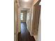Hallway with hardwood floors leading into rooms with tile flooring and an open door at 4706 Dragon Tail Ct, Valrico, FL 33594