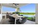Covered outdoor dining area with a built-in grill, lake views, and ample seating for entertaining at 14448 Woodland Preserve Trl, Parrish, FL 34219