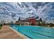 Large community pool with multiple lap lanes and a modern red and gray clubhouse at 42850 Park View Dr, Punta Gorda, FL 33982