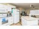 Bright kitchen with white appliances and cabinets, adjacent to living area at 6310 Cecelia Dr, New Port Richey, FL 34653