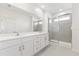 Modern bathroom with double vanity, large mirror, and glass-enclosed shower with gray tile at 17330 Alderwood Ln, Punta Gorda, FL 33982