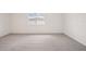 An empty bedroom with neutral carpeting and a window with natural light at 1775 Draughton Dr, Zephyrhills, FL 33541