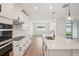 Modern kitchen boasts stainless appliances, sleek white cabinetry, stone countertops, and wood tile flooring at 1775 Draughton Dr, Zephyrhills, FL 33541