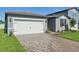 Exterior of home showing the brick paver driveway, two-car garage, and well-kept lawn at 1817 Draughton Dr, Zephyrhills, FL 33541