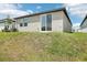 Home's backyard features a stucco wall, sliding glass door and a grassy, sloped yard at 3539 Moscato Dr, Brooksville, FL 34602