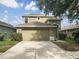 Two-story home with a two-car garage and landscaped bushes, set against a blue sky with clouds at 10429 Avelar Ridge Dr, Riverview, FL 33578