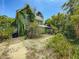 Two-story green house exterior with mature vegetation and a pathway, showcasing a rustic charm and potential for landscaping at 226 N Grosse Ave, Tarpon Springs, FL 34689