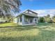 View of the home's backyard, with green grass, mature trees, and covered patio at 5009 Clover Mist Dr, Apollo Beach, FL 33572