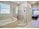 Bathroom featuring a corner tub, glass-enclosed shower, and window for natural light and ventilation at 5009 Clover Mist Dr, Apollo Beach, FL 33572