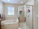 Bathroom showcasing a tub, glass shower, and neutral color palette for a spa-like retreat at 5009 Clover Mist Dr, Apollo Beach, FL 33572
