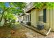View of backyard featuring trees, rocks, AC units, and exterior building features at 609 S Glen Ave # E, Tampa, FL 33609