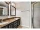 Bathroom with granite countertops, dual sinks, framed mirrors, and walk-in shower at 609 S Glen Ave # E, Tampa, FL 33609