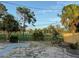 Fenced-in back yard with gravel, view of the recreational field and wooded area, including palm trees at 3680 Whiting Se Dr, St Petersburg, FL 33705