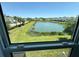 Scenic view of a community pond with lush greenery and palm trees from a large window at 4171 Via Sienna Cir, Sarasota, FL 34243