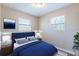Cozy bedroom featuring a plush blue bed, soft lighting, and two bright windows at 3850 11Th S Ave, St Petersburg, FL 33711