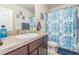 Cozy bathroom with a floral shower curtain, wood cabinetry and a white sink at 819 Lucent Sands Ct, Brandon, FL 33511