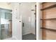 Modern bathroom with a glass enclosed shower, wood shelving, decorative flooring, and access to a custom walk-in closet at 20323 Granlago Dr, Venice, FL 34293