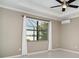 Neutral bedroom with hardwood floors, a tray ceiling with a fan, and a large window providing a view of the backyard at 20323 Granlago Dr, Venice, FL 34293