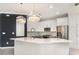 Modern kitchen with white cabinets, stainless steel appliances, a center island with seating, and decorative hanging light fixtures at 20323 Granlago Dr, Venice, FL 34293
