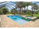 Beautifully designed pool and spa area under a screened enclosure, surrounded by tropical landscaping at 20323 Granlago Dr, Venice, FL 34293