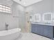Luxurious bathroom featuring a soaking tub, walk-in shower, and elegant vanity with lighted mirrors at 4413 W Wallcraft Ave, Tampa, FL 33611
