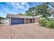 Brick driveway leading to a single car garage with lush landscaping around the exterior of the house at 8701 Thornwood Ln, Tampa, FL 33615