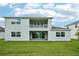 Rear exterior view shows the covered patio, second story balcony, and well-maintained lawn at 9201 Sanders Tree Loop, Wesley Chapel, FL 33545
