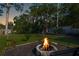 Landscaped backyard with a stone fire pit, mature trees, and lush green lawn at 5141 Mallet Dr, Port Richey, FL 34668